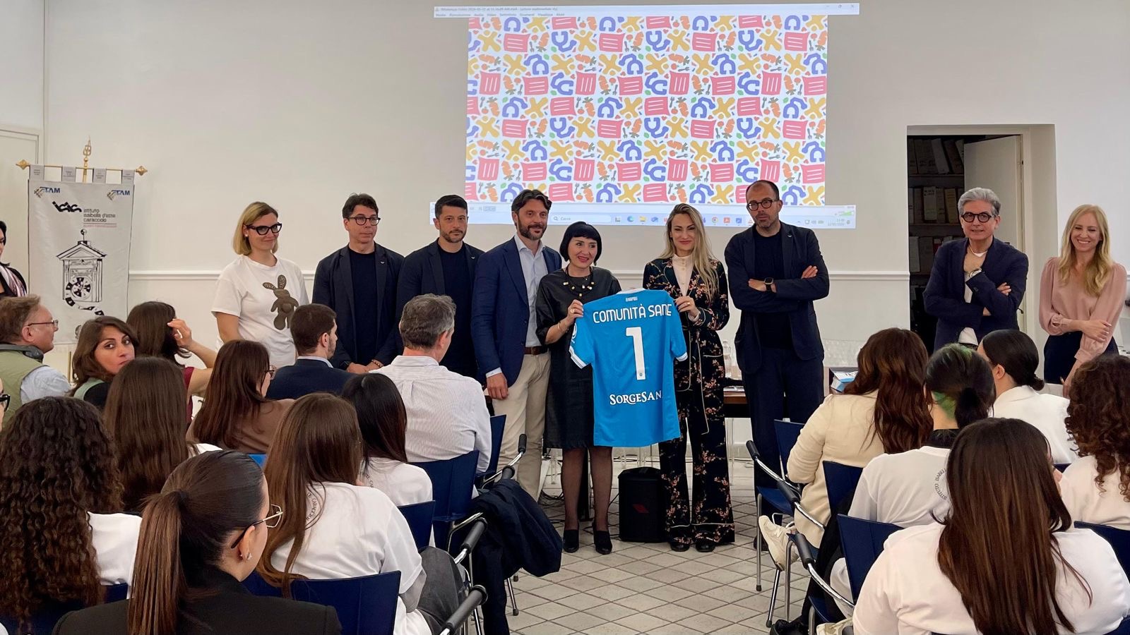 Relatori e professionisti del progetto Comunità S.A.N.E. con la maglia celebrativa SSC Napoli, Istituto Isabella D'Este Caracciolo, Napoli, maggio 2026